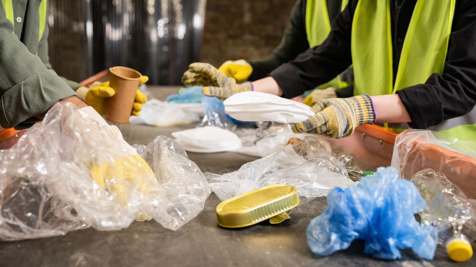 [Translate to Englisch:] Hände sortieren Müll aus der Gelben Tonne auf einem Sortierband